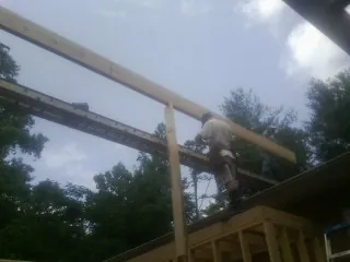 Carpenter setting a ridge beam over a new addition frame — Ice Dam Removal by Roofing Brothers in Connell