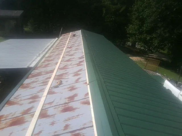 Old rusted panels beside newly installed green metal roofing — Wind Damage Roof Repair by Roofing Brothers in Connell