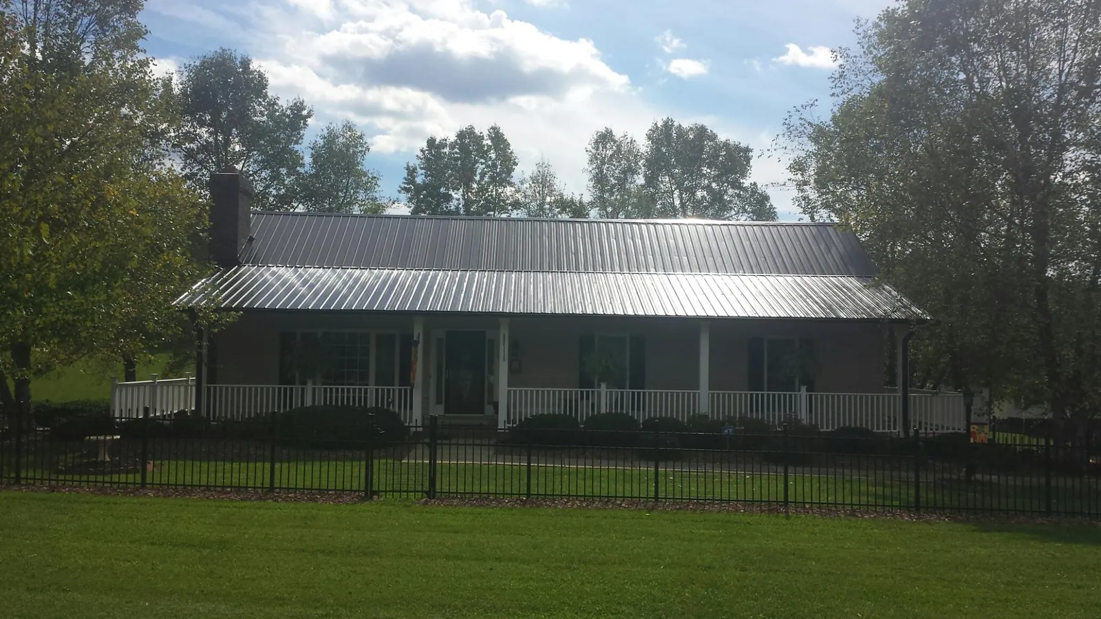 Gray metal roof on a brick ranch with a full width front porch — Gutter Guard Installation work by our crew in Connell