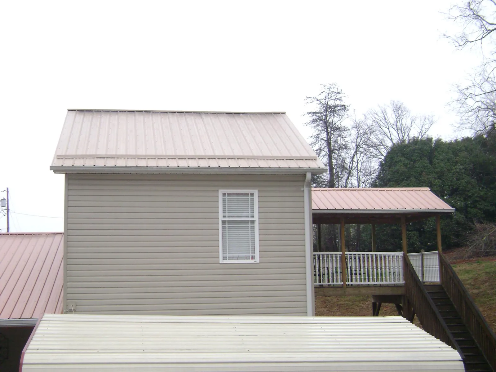 Tan metal roofs on a two story addition and attached porch, from a Roof Replacement job in Connell