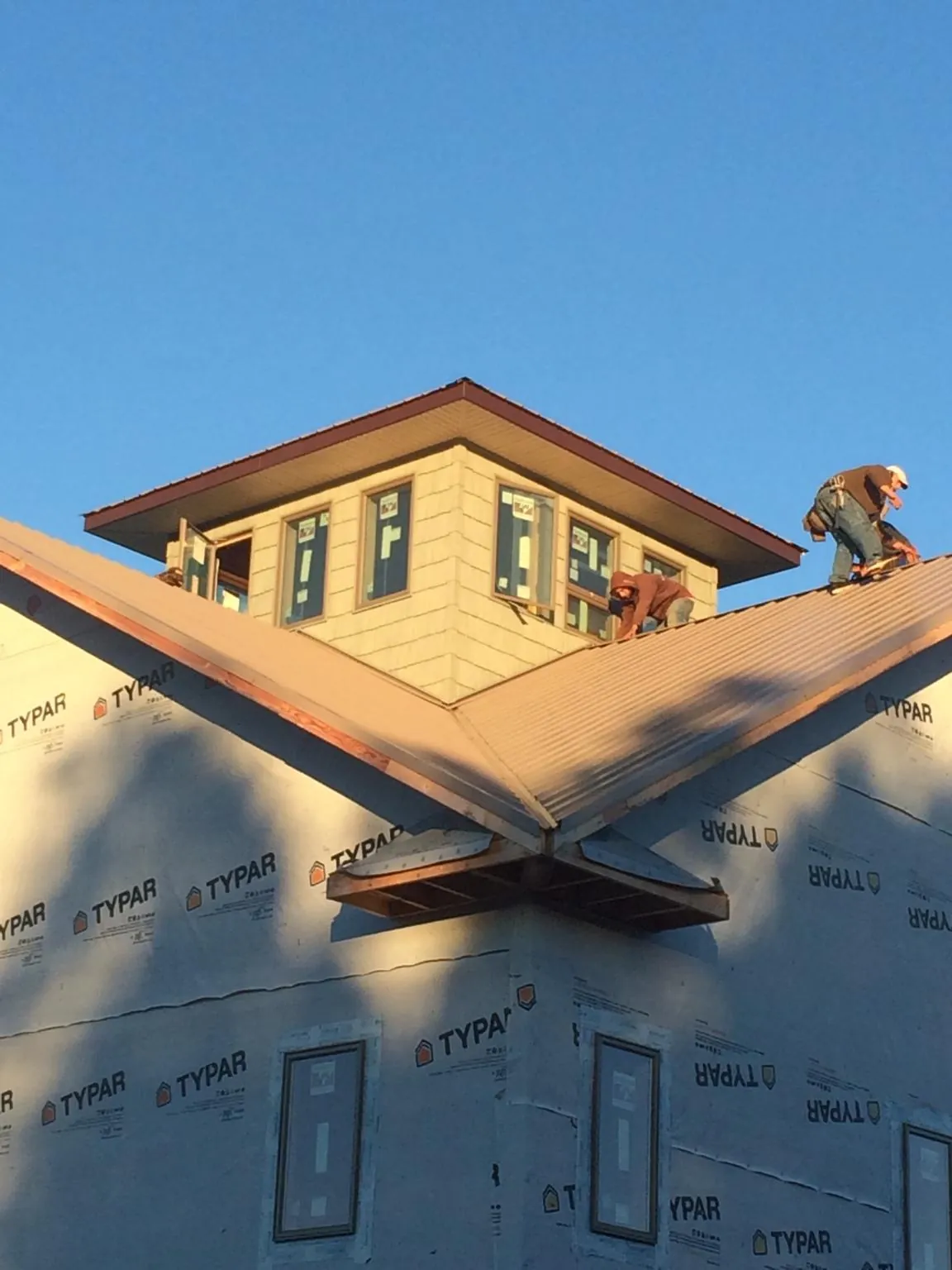 Roofers working around a rooftop cupola on a new metal roof at sunset — Roof Waterproofing in Connell by Roofing Brothers